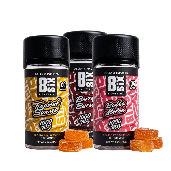 Three bottles of Eighty Six Brand Delta 8 Gummies by Eighty Six Brand featuring tropical fruit-flavored delights: Tropical Sunset, Berry Burst, and Bubba Melon. Bottles are labeled 1000 mg, with a few orange gummies in front. These indulgent treats contain hemp-derived Delta 8 THC for the perfect blend of taste and relaxation.