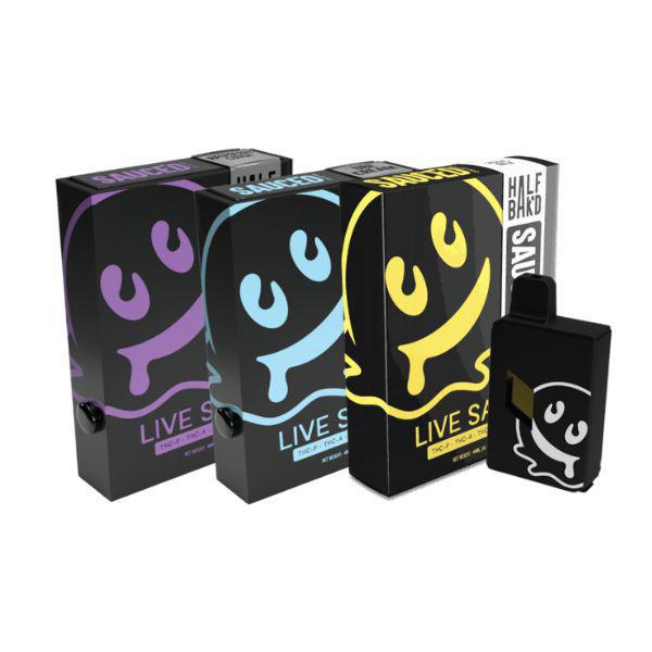 Three colorful boxes and a black device with a cartoon ghost design on them. The text on the boxes reads "Live Sauce" and "Half Saked." These items, part of the Half Bak'd Collection, appear to be THC-A live resin disposable vape products.