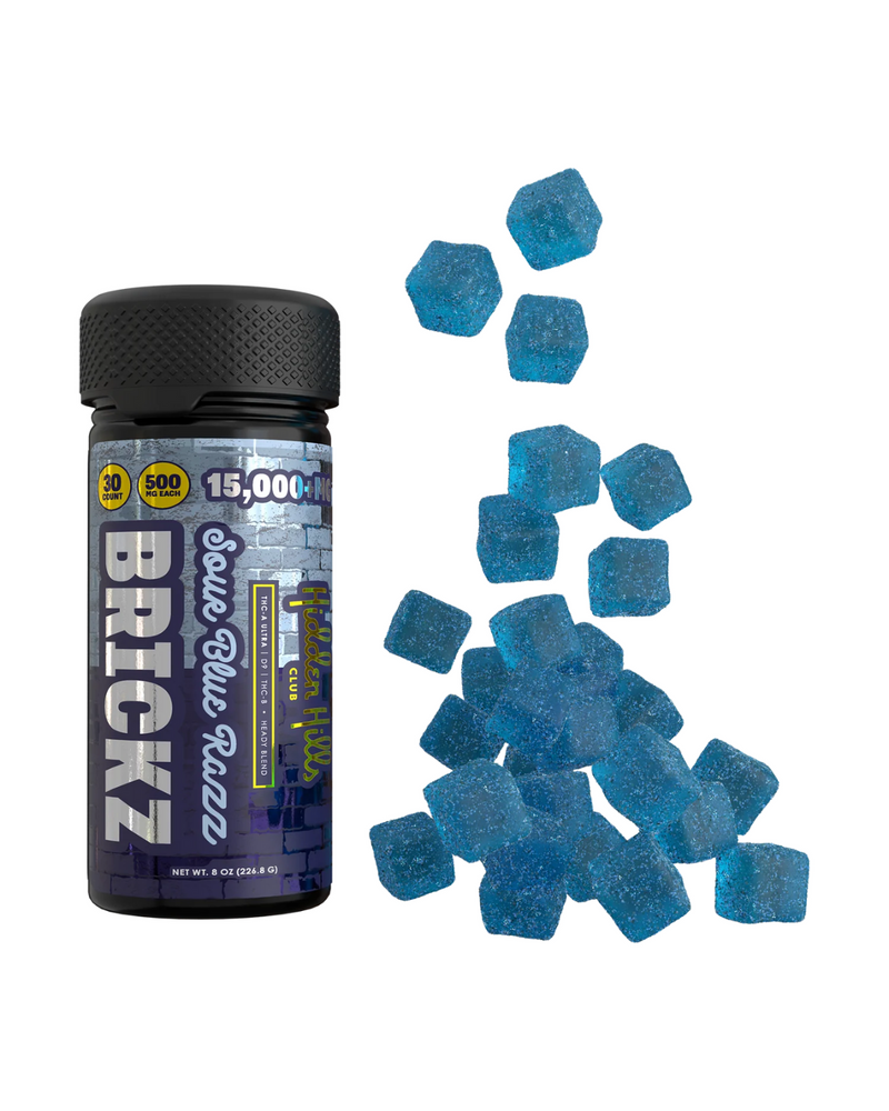 A bottle labeled "Hidden Hills Heady Blend Brickz Gummies | 15000mg" sits next to a pile of blue, sugar-coated gummy candies shaped like small bricks, each infused with Delta 11 THC for an extra kick.