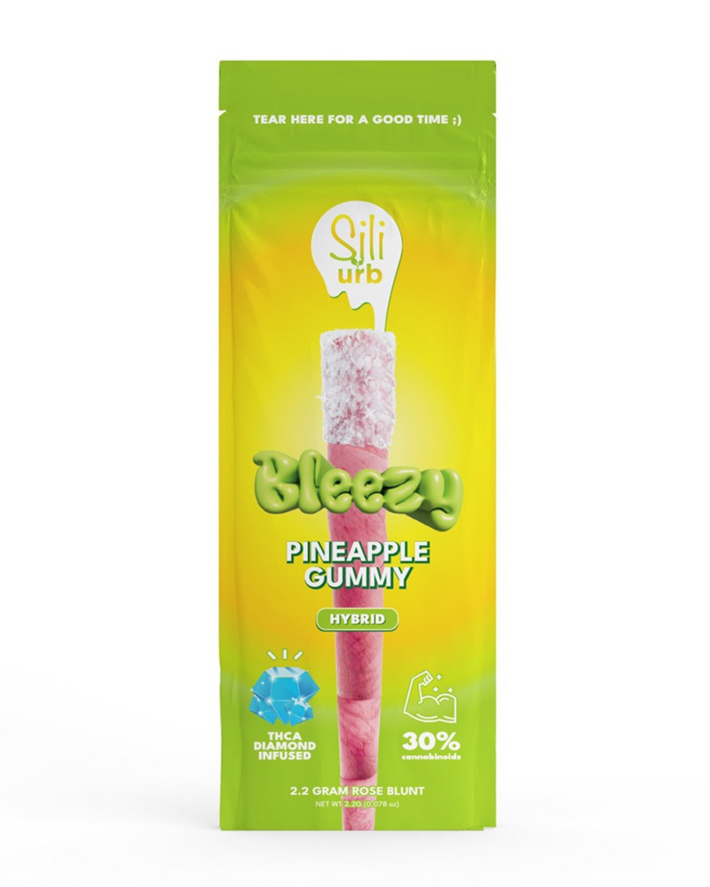 The Sili x Urb Bleezy THCA Snow Capped Preroll | 2.2g is presented in striking green and yellow packaging and features a THC-infused rose blunt. It contains 30% indoor exotic flower, 0.3 grams of concentrate, and is enhanced with Urb Saucy THC Diamonds for a luxurious experience.